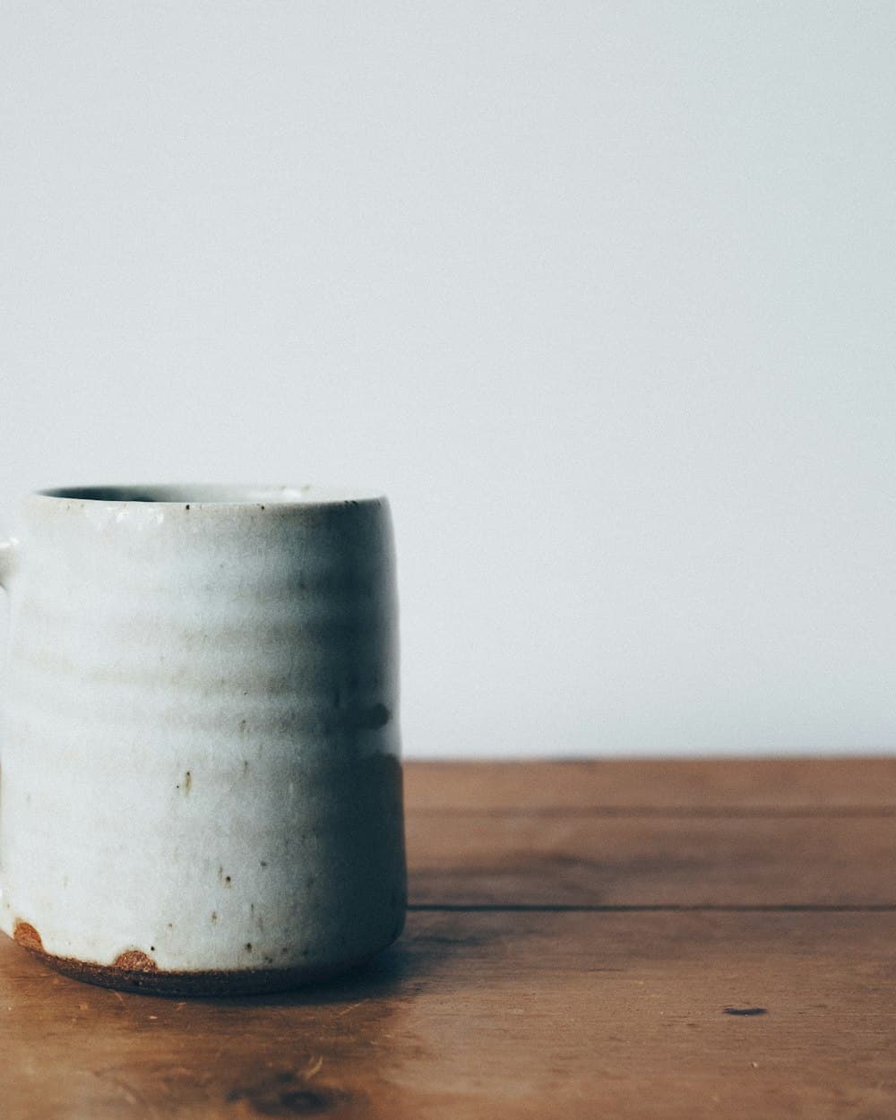 Jarro de cerámica gris claro sobre una mesa de madera
