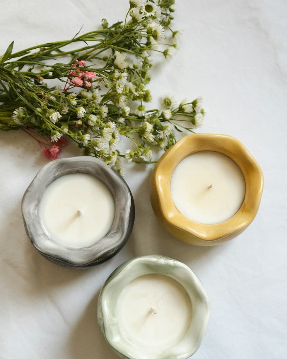 Portavelas de cerámica con velas encendidas y flores secas