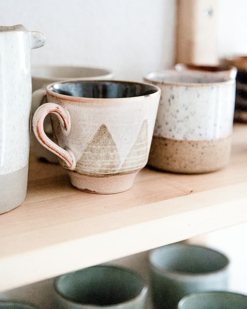 Tazas de cerámica artesanal apoyadas en un estante de madera