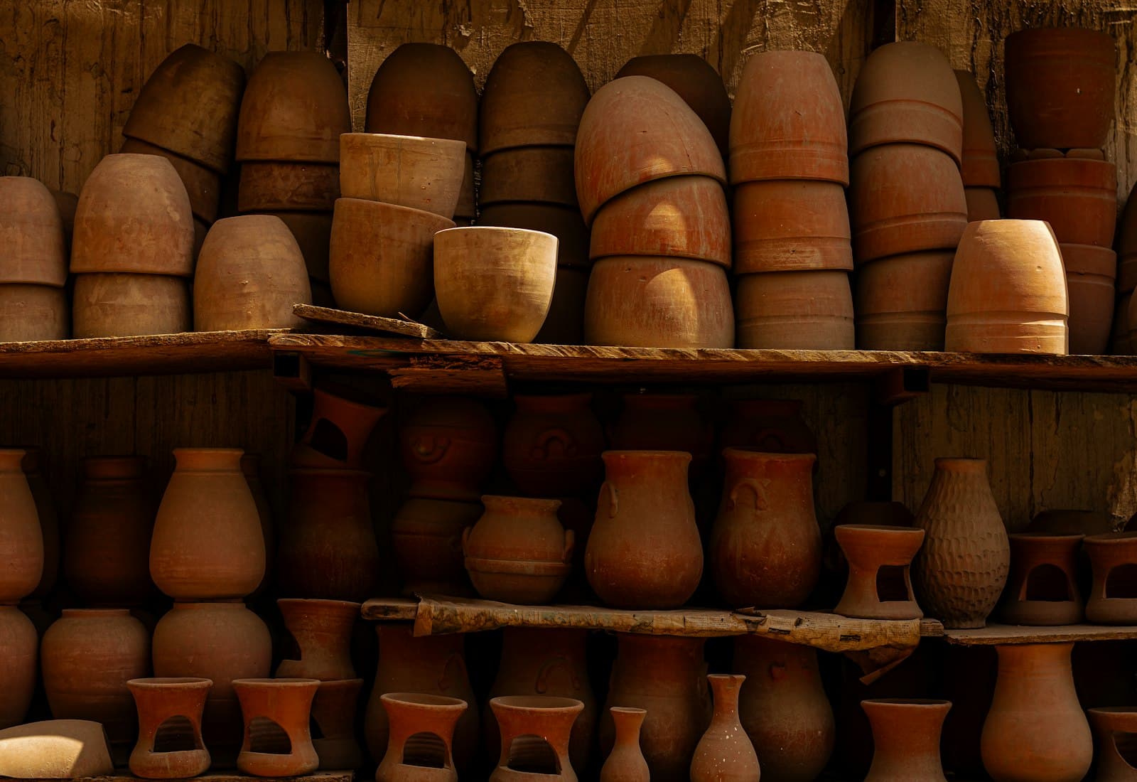 Macetas de terracota apiladas en los estantes del taller